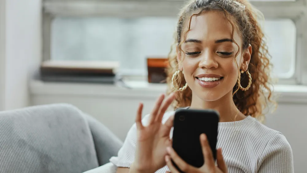 ALT Text: a girl sitting watching an ad on her phone